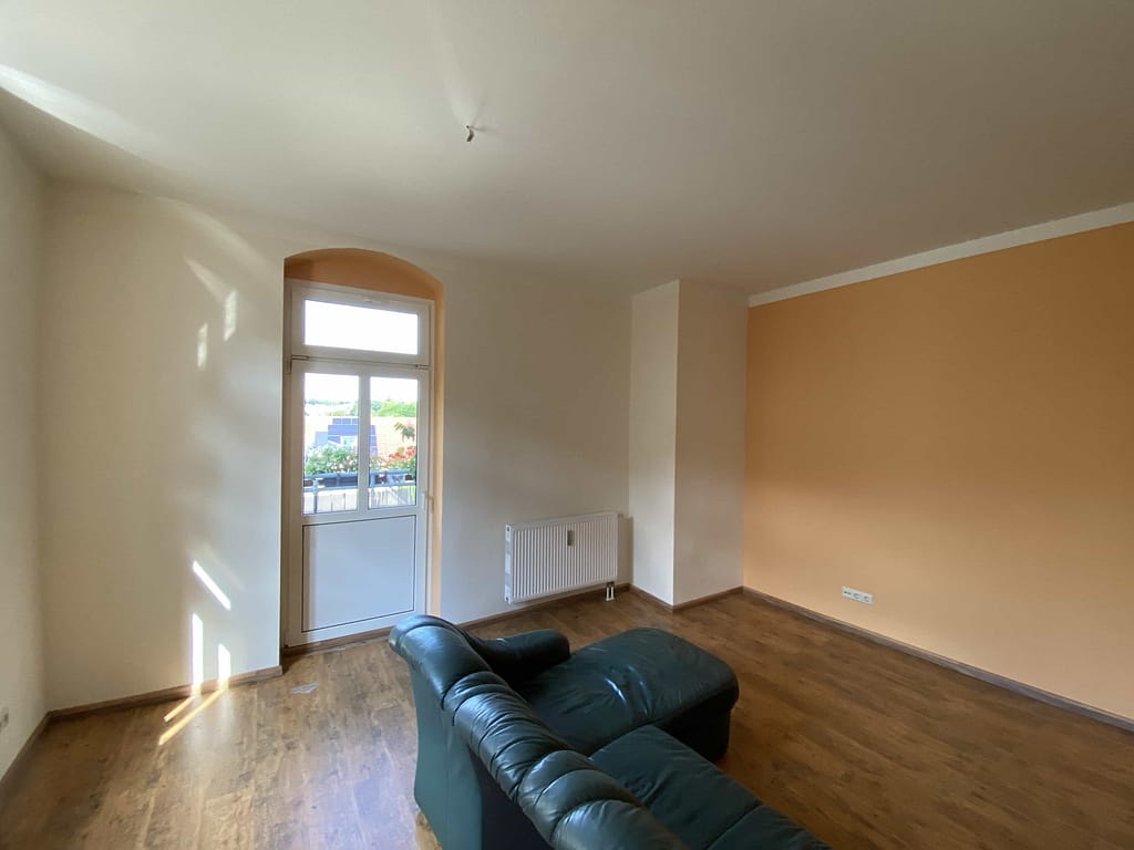 Wohnzimmer mit Holzboden und Tür zum Balkon