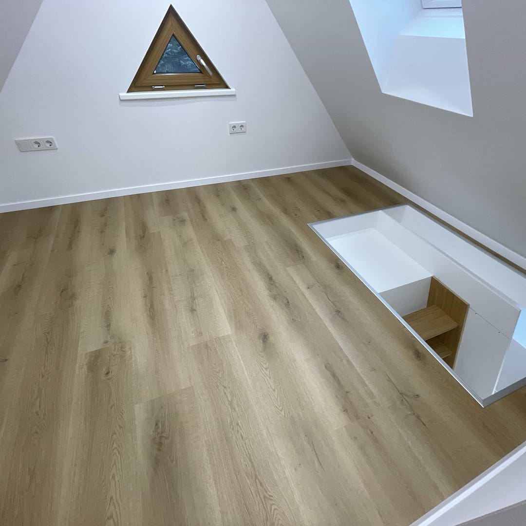 Dachbodenzimmer mit Holzfußboden und kleinem Fenster.